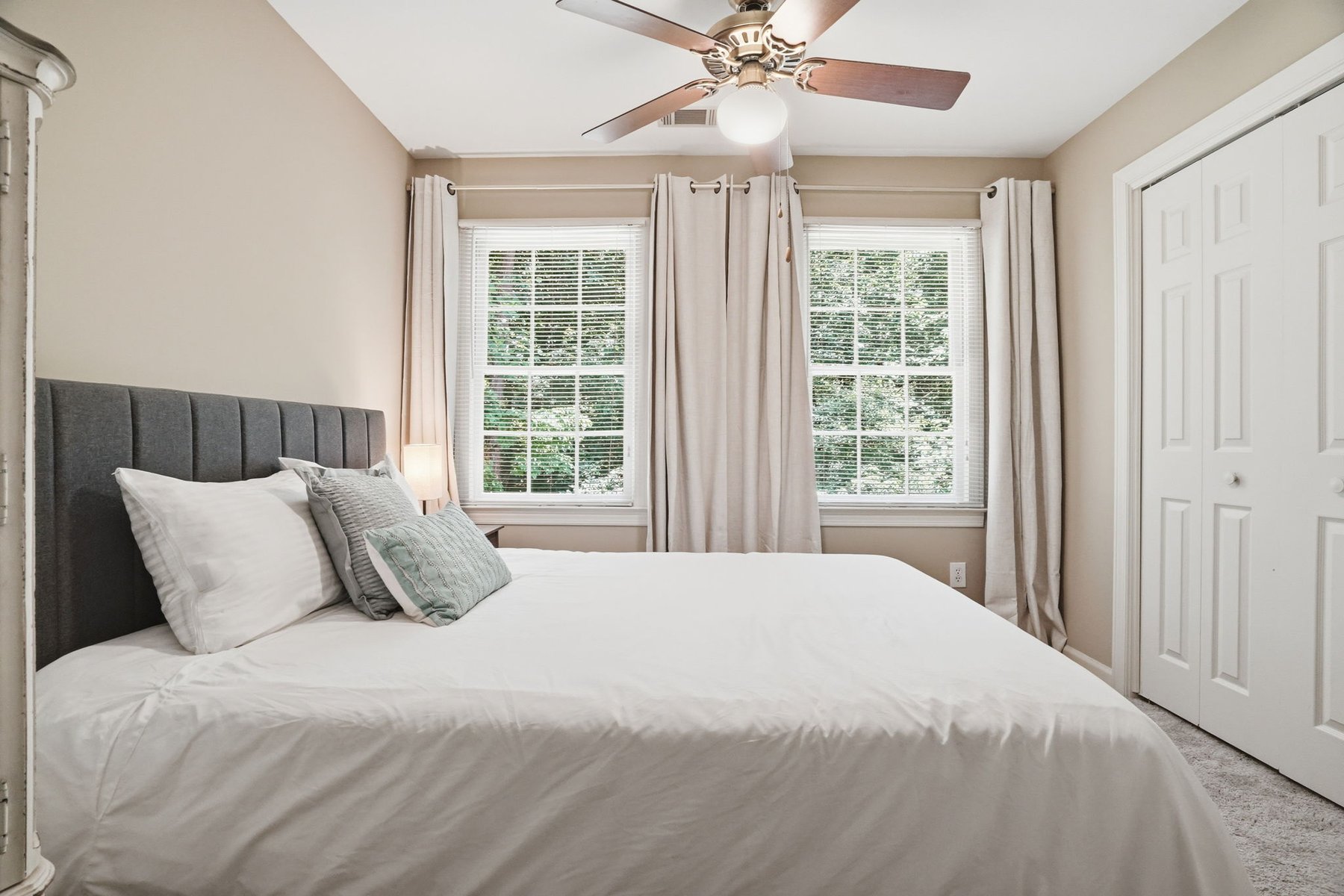 Bedroom with neutral bedding and ceiling fan